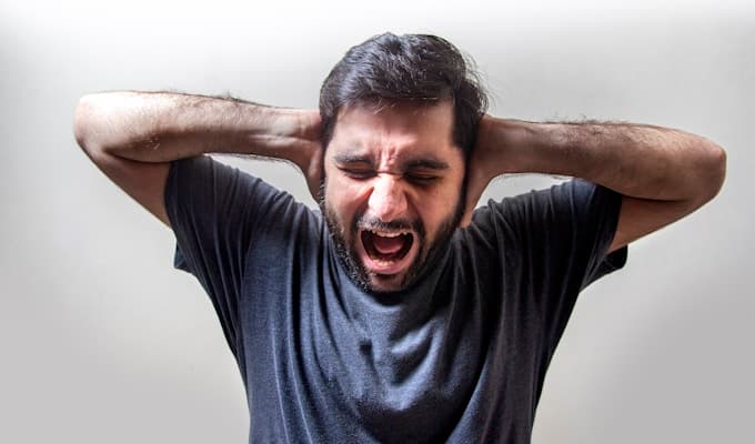 Man screaming in frustration, hands on head